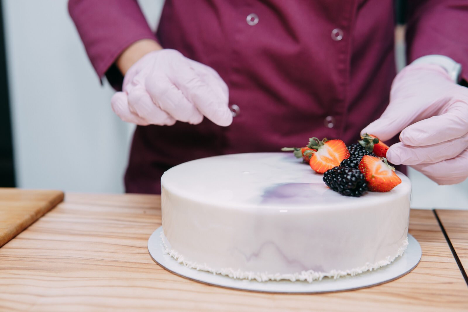 Pastry chef decorating a cake with strawberries